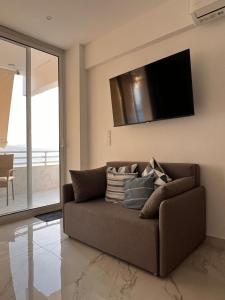 a brown couch in a living room with a flat screen tv at Ble Property Atlas 6 in Loutraki