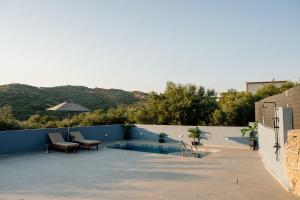 a patio with a pool and chairs and an umbrella at Angels luxury villa in Kastamonítsa