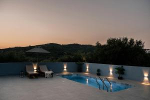 a swimming pool with a table and chairs and an umbrella at Angels luxury villa in Kastamonítsa