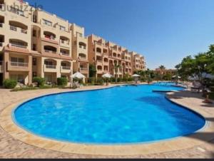 a large blue swimming pool in front of a building at Agora resort north coast in Dawwār Abū Maḩrūs