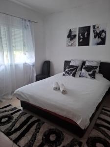 a bedroom with a large white bed with slippers on it at Studio apartman Delic in Podgorica