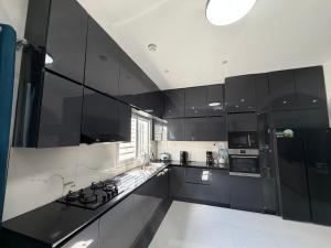 a large kitchen with black cabinets and appliances at C-Appart Residence in Tuléar
