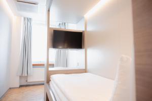 a bedroom with a bed with a tv on the wall at Omena Hotel Helsinki Lönnrotinkatu in Helsinki