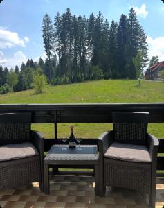 a patio with two chairs and a table with a bottle of wine at Hotel Vuković in Han Pijesak