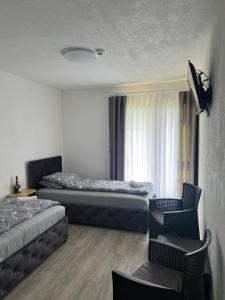 a hotel room with two beds and a chair at Hotel Vuković in Han Pijesak