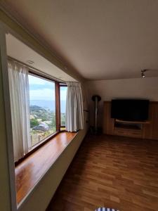 a living room with a large window and a flat screen tv at Portezuelo in Zapallar