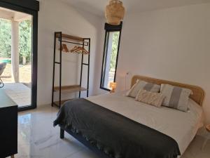 a bedroom with a bed and a large window at Résidence Les Jardins du Piale in Bonifacio