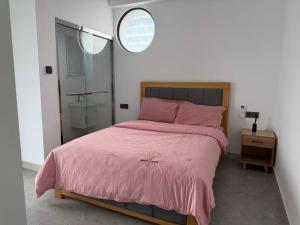 a bedroom with a pink bed and a mirror at Chouke Maison in Abidjan