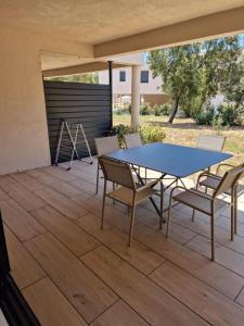 a patio with a table and chairs on a deck at Résidence Les Jardins du Piale in Bonifacio