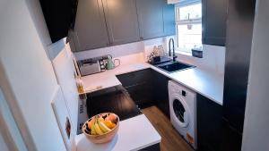 a small kitchen with a bowl of fruit on a counter at Luxurious Modern Town House in Gillingham +2 photos