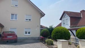 a white house with a red car parked in the driveway at Ferienwohnung Bayer in Gründau