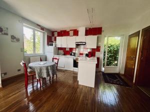 a kitchen with a table and red and white cabinets at La Maison d Ingrandes - relais Valami in Ingrandes-de-Touraine
