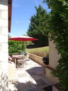 a patio with a table and a red umbrella at La Maison d Ingrandes - relais Valami in Ingrandes-de-Touraine +3 photos
