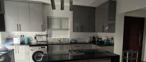 a kitchen with white cabinets and a washing machine at Naomy's Place in Harare