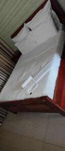 a bed with white sheets and pillows on it at Naomy's Place in Harare