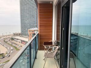 a balcony with a chair and a view of the ocean at Batumi - Seaside Stunning Apartment in Batumi