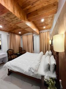 a bedroom with a large bed with a wooden ceiling at Pine Cottage in Murree