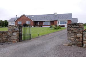 a brick house with a gate and a stone wall at Short Strand Dingle in Dingle