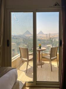 a room with a glass door with a table and chairs at Grand Museum with Pyramids view inn in Cairo