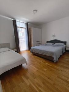 a bedroom with two beds and a wooden floor at Apartmani Orlović Bar in Bar
