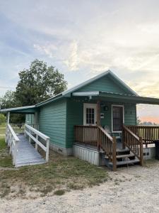 a green house with a porch and a deck at Turn On Inn in Lake Village