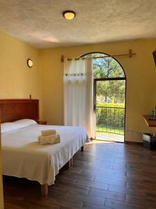 a bedroom with a bed and a large window at HOTEL RESTAURANT LOS PRISMAS in Huasca de Ocampo