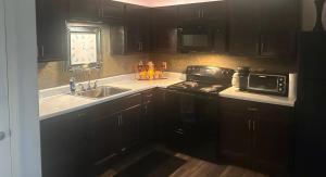 a kitchen with black cabinets and a stove and a sink at Union at the loop in Lawrence