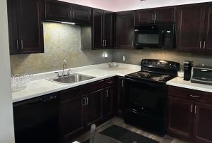 a kitchen with black cabinets and a sink and a stove at Union at the loop in Lawrence