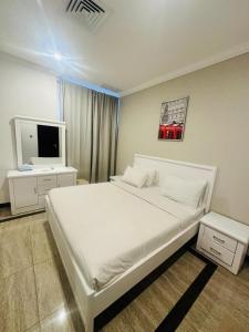 a bedroom with a white bed and a television at Leader Hotels Salmiya in Kuwait