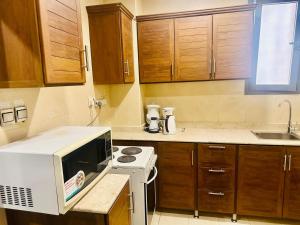 a small kitchen with a microwave and a stove at Leader Hotels Salmiya in Kuwait