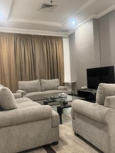 a living room with couches and a flat screen tv at Leader Hotels Salmiya in Kuwait +16 photos