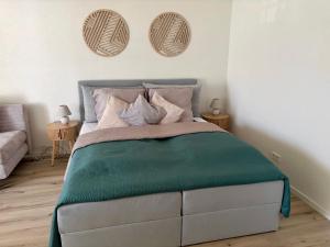 a bedroom with a bed with green sheets and pillows at Darius Apartment Kehl in Kehl am Rhein