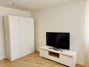a living room with a tv and a white cabinet at Darius Apartment Kehl in Kehl am Rhein