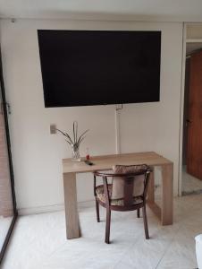 a wooden table with a chair and a television on a wall at Villa del Tesoro in El Poblado