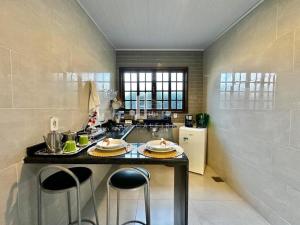 a kitchen with a counter with two stools in it at Loft em Teresópolis in Teresópolis