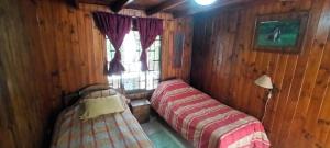 two beds in a room with a window at Cabaña Los Corsarios in El Quisco