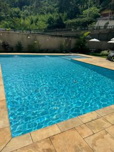 a swimming pool with blue water in a yard at Loft em Teresópolis in Teresópolis