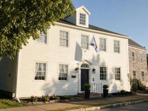 a white house with a flag on it at Bailey House Inn - Georgian Waterfront Retreat in Annapolis Royal