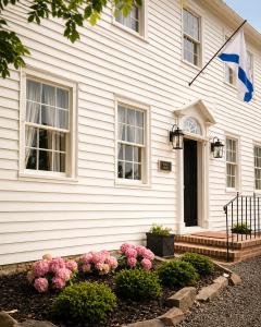 a white house with a flag on it at Bailey House Inn - Georgian Waterfront Retreat in Annapolis Royal