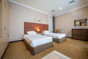 a hotel room with two beds and a dresser at Kingsgate Hotel Doha by Millennium Hotels in Doha