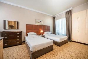 a hotel room with two beds and a television at Kingsgate Hotel Doha by Millennium Hotels in Doha