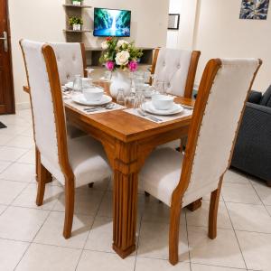 a wooden dining room table with white chairs at 1 bedroom apartment in shanzu near pride inn resort in Mombasa