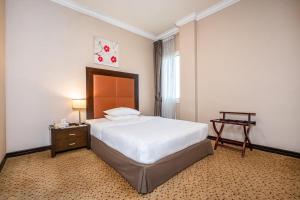 a bedroom with a bed and a table and a clock at Kingsgate Hotel Doha by Millennium Hotels in Doha