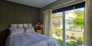 a bedroom with a bed and a large window at Coastal Harmony B&B in Portstewart