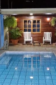 a swimming pool with two white chairs and a house at Ujarrás Getaway with Private Pool in Ujarrás