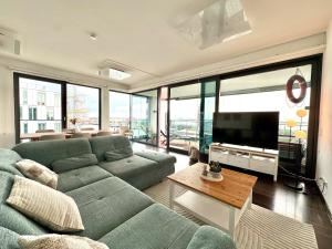 a living room with a green couch and a television at Bheaven I Captains Apartment in Bremerhaven