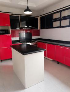 a kitchen with red cabinets and a black counter top at Maison Madame - Female only Shared Apartment Lekki in Lekki