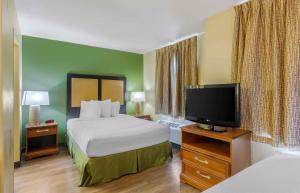 a hotel room with a bed and a flat screen tv at Extended Stay America Suites - Richmond - W Broad Street - Glenside - North in Richmond