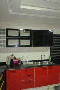 a kitchen with red cabinets and a sink at Maison Madame - Female only Shared Apartment Lekki in Lekki +59 photos