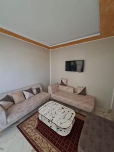 a living room with a couch and a flat screen tv at Omaima villa in Taguermess